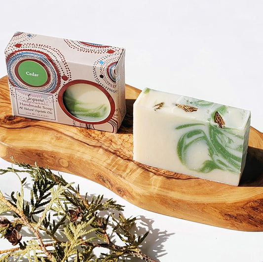 Handmade soap with green marbling on a wooden tray, next to its packaging.