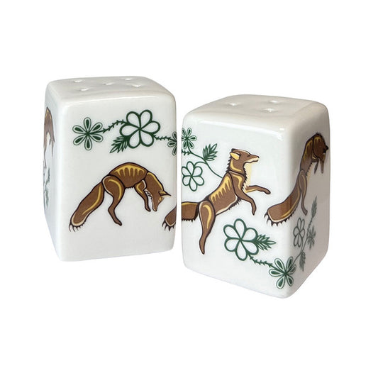 Two ceramic salt and pepper shaker with fox and clover designs on a white background