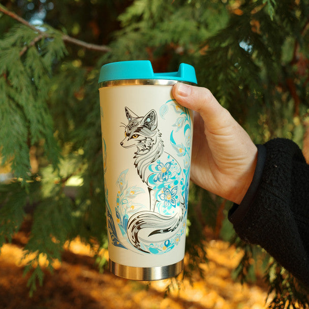 Person holding a tumbler with a fox design against a natural background