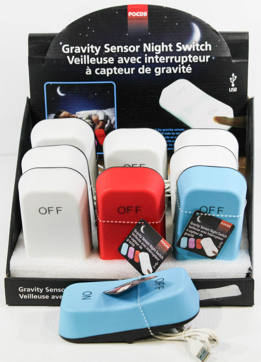 A retail display box of FOCUS Gravity Sensor Night Switches, showing multiple units in white, red, and light blue, with one light blue unit in the foreground connected to a USB cable.
