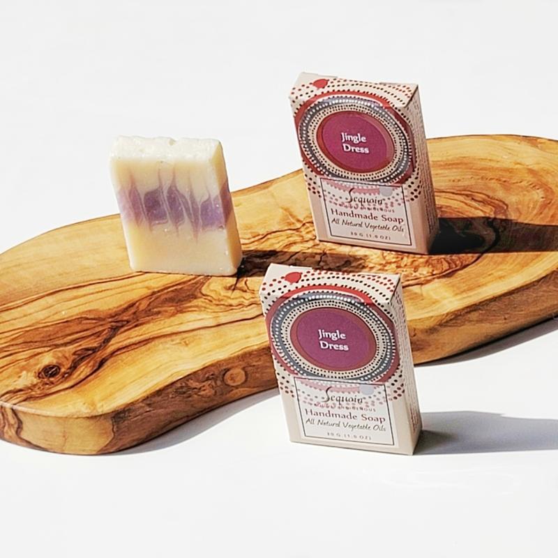 Two boxes of 'Jingle Dress' soap on a wooden surface with a white background