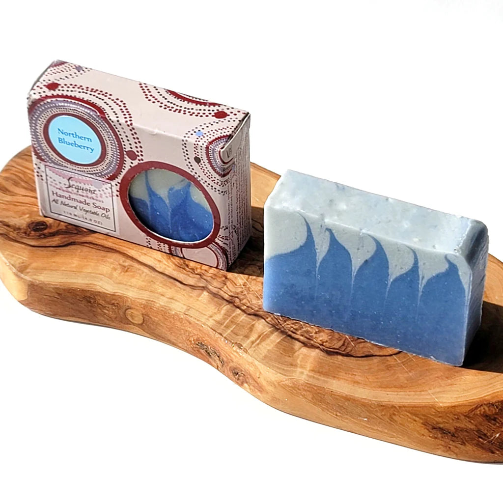 Blue and white soap bar on a wooden tray with packaging in the background
