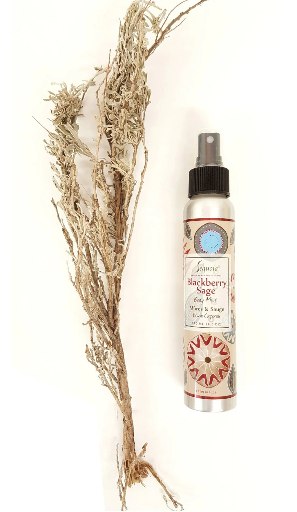 Spray bottle with decorative label next to dried herbs on a white background