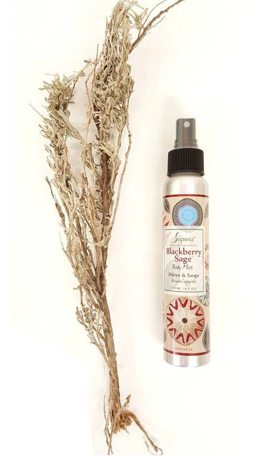 Spray bottle with decorative label next to dried herbs on a white background