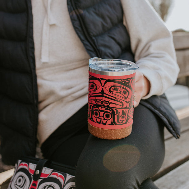 Person holding a red and black patterned tumbler outdoors